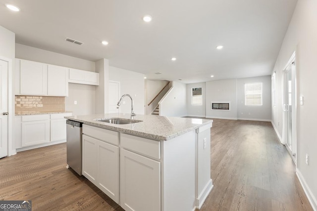 kitchen with visible vents, dishwasher, a kitchen island with sink, white cabinetry, and a sink