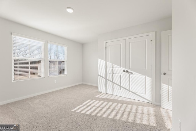 unfurnished bedroom with light carpet, baseboards, and a closet