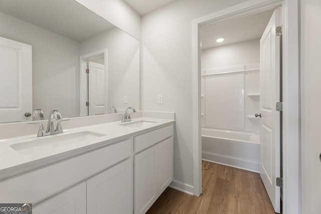 bathroom featuring double vanity, baseboards, a sink, and wood finished floors