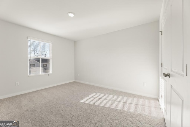 empty room featuring baseboards and light colored carpet