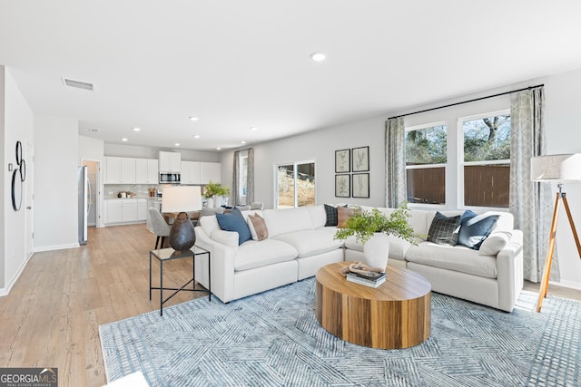 living room featuring light wood-style flooring, visible vents, a wealth of natural light, and recessed lighting