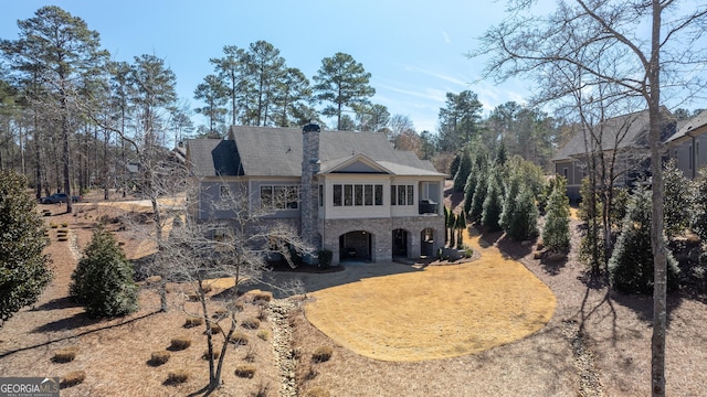 rear view of house featuring stone siding and a chimney