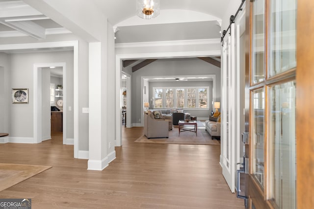 entryway with lofted ceiling with beams, light wood-style flooring, baseboards, and a barn door