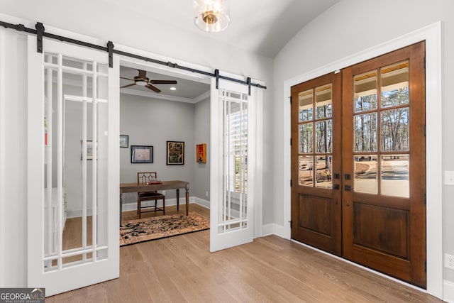 entryway featuring french doors, lofted ceiling, a barn door, wood finished floors, and baseboards