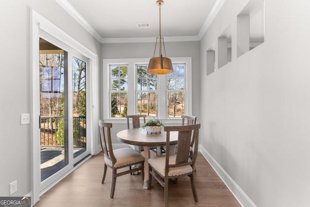 dining space with visible vents, crown molding, baseboards, and wood finished floors