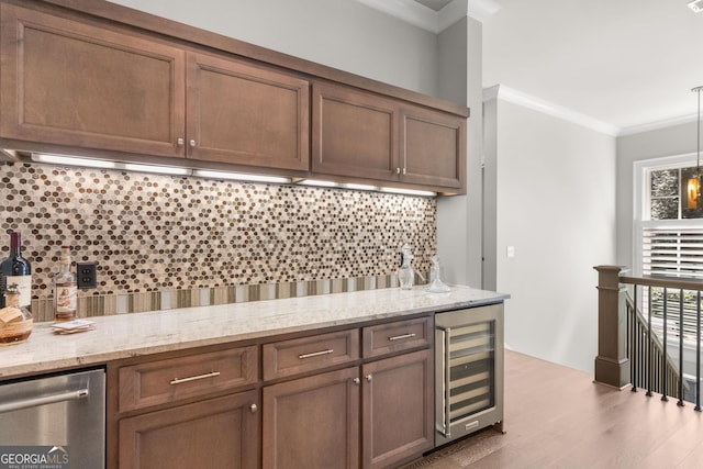 kitchen featuring light stone counters, beverage cooler, hanging light fixtures, tasteful backsplash, and crown molding