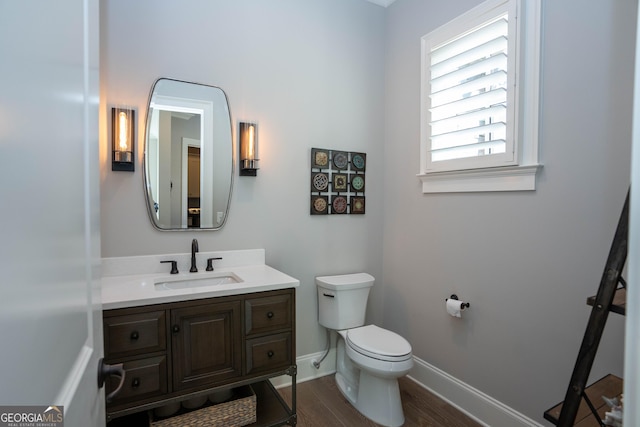 bathroom featuring wood finished floors, vanity, toilet, and baseboards