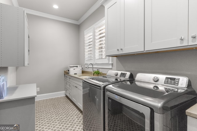 laundry room featuring a sink, baseboards, ornamental molding, cabinet space, and washer and clothes dryer