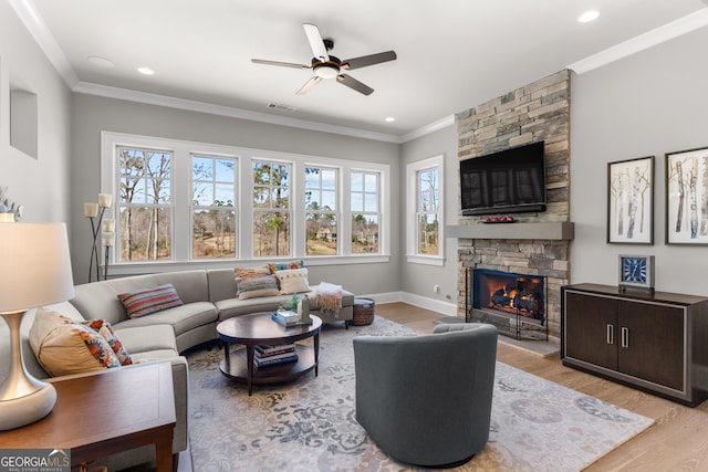 living area with a fireplace, light wood-style flooring, and crown molding