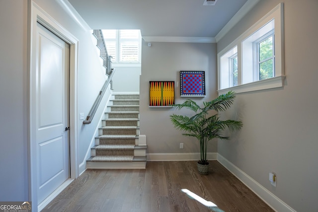 stairs featuring ornamental molding, wood finished floors, visible vents, and baseboards