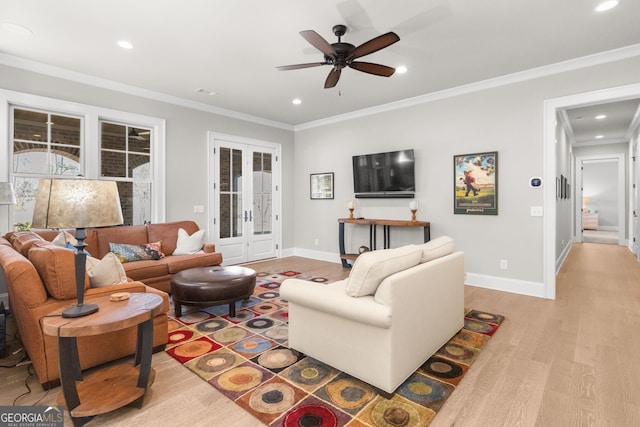 living room featuring light wood-style floors, baseboards, ornamental molding, and french doors