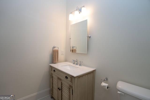 half bathroom featuring toilet, baseboards, and vanity