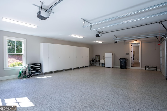 garage featuring a sink, freestanding refrigerator, and a garage door opener