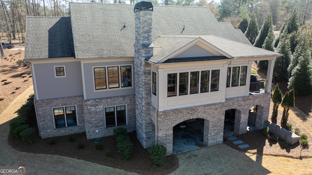 view of front of home featuring a standing seam roof, brick siding, a chimney, and a shingled roof