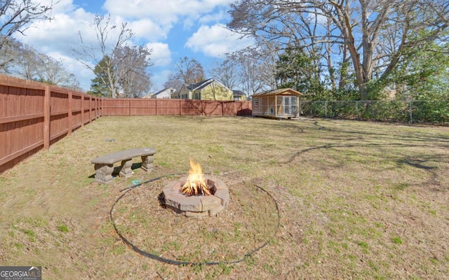 view of yard featuring a storage unit, an outdoor fire pit, an outdoor structure, and a fenced backyard