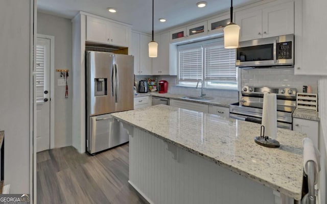 kitchen with stainless steel appliances, white cabinets, a sink, and hanging light fixtures