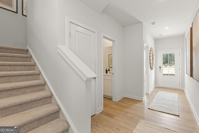 entryway with light wood finished floors, stairs, and baseboards