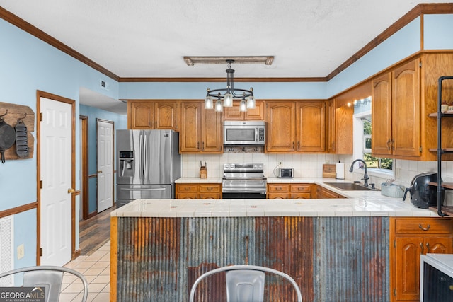 kitchen with hanging light fixtures, brown cabinetry, stainless steel appliances, and a sink