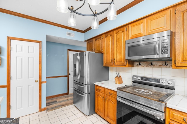 kitchen with appliances with stainless steel finishes, brown cabinetry, visible vents, and ornamental molding