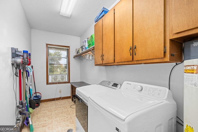 laundry room with a textured ceiling, separate washer and dryer, cabinet space, and baseboards