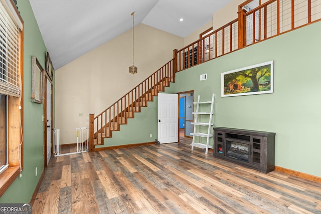 1617 Dublin Eastman Rd, Dexter, GA 31019 - unfurnished living room with high vaulted ceiling, wood finished floors, baseboards, stairway, and radiator heating unit
