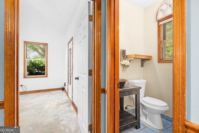 half bathroom featuring vaulted ceiling, toilet, and baseboards