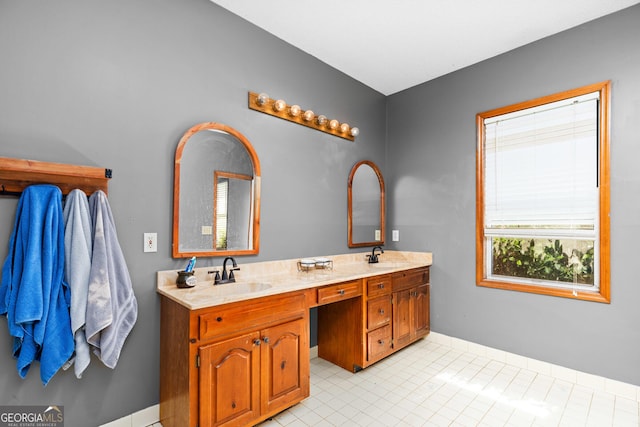 bathroom featuring double vanity, baseboards, a sink, and tile patterned floors