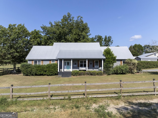 view of front of property featuring metal roof, a porch, a front yard, and fence