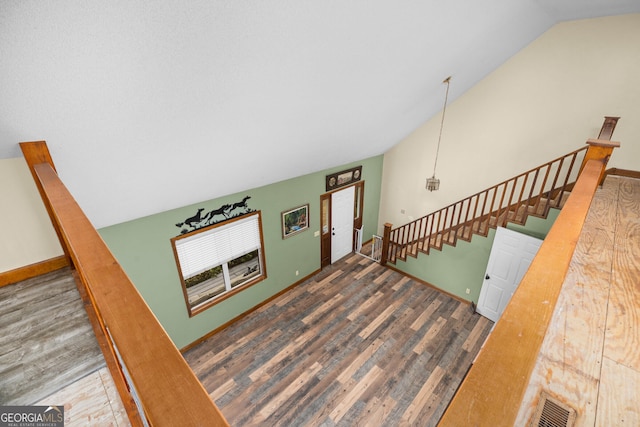 interior space featuring lofted ceiling, wood finished floors, visible vents, and baseboards