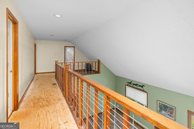 hallway featuring vaulted ceiling, an upstairs landing, and baseboards