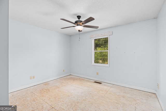 unfurnished room with a textured ceiling, ceiling fan, visible vents, and baseboards