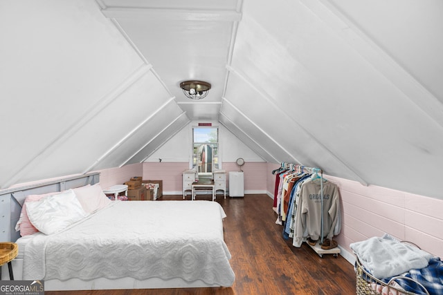 bedroom with vaulted ceiling, dark wood-type flooring, and wooden walls