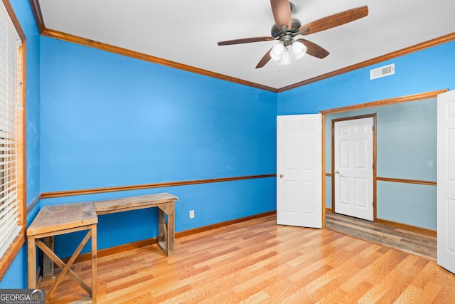 interior space with light wood-style floors, visible vents, ornamental molding, and ceiling fan