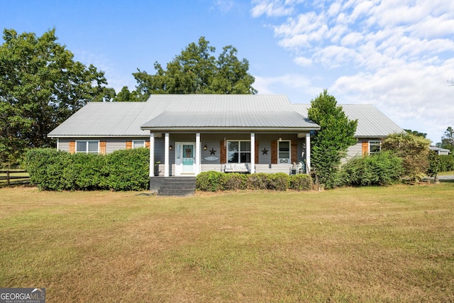 view of front facade with a porch, metal roof, and a front lawn