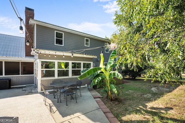 back of house with a patio area, metal roof, and a chimney