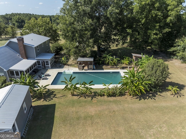 outdoor pool featuring a sunroom, a patio area, and a yard