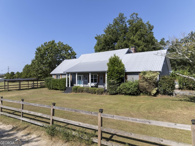 view of front of property with a porch, metal roof, fence, and a front lawn