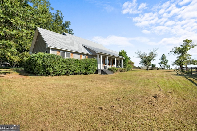 view of front of home with metal roof, fence, and a front lawn