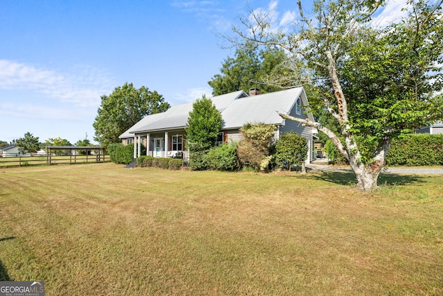 exterior space featuring metal roof, a porch, fence, and a front lawn