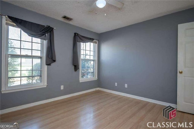 unfurnished room featuring baseboards, visible vents, a ceiling fan, a textured ceiling, and light wood-style floors