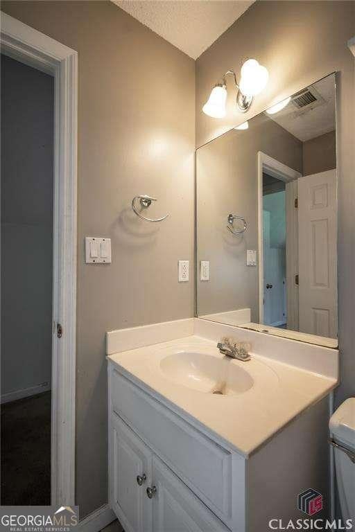 bathroom featuring toilet, visible vents, and vanity