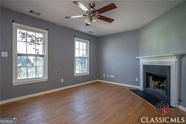 unfurnished living room featuring visible vents, a fireplace with raised hearth, light wood-style flooring, and baseboards