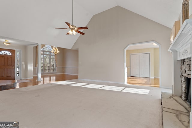 unfurnished living room with a fireplace, light carpet, high vaulted ceiling, baseboards, and ceiling fan with notable chandelier