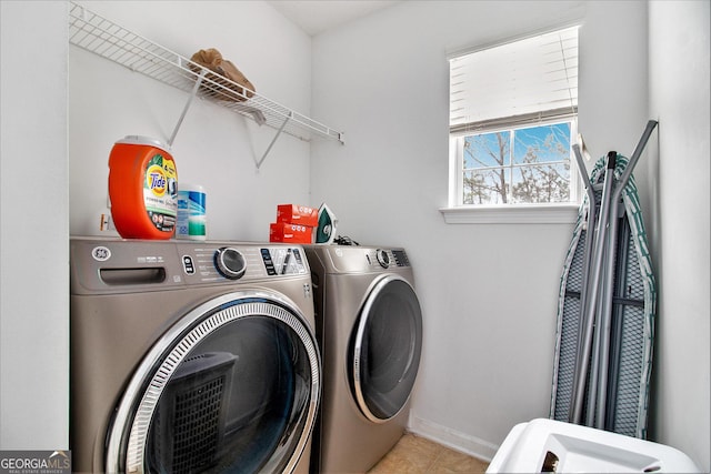 washroom with laundry area, light tile patterned flooring, independent washer and dryer, and baseboards