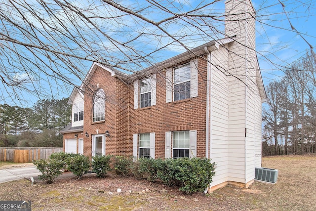 view of property exterior with concrete driveway, a chimney, an attached garage, fence, and brick siding