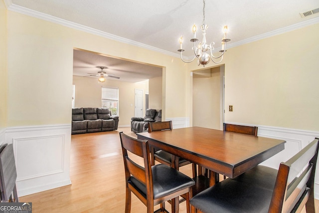 dining room with ornamental molding, wainscoting, visible vents, and light wood-style floors