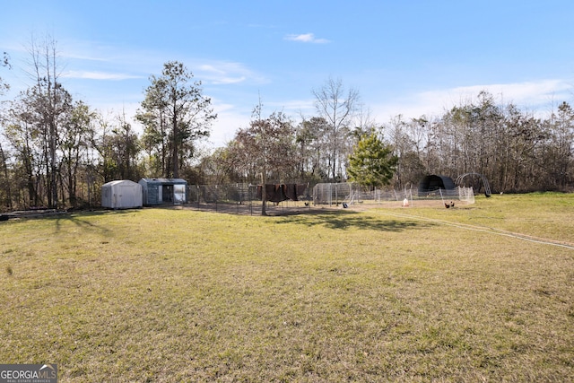 view of yard featuring a storage shed, a carport, an outdoor structure, and fence