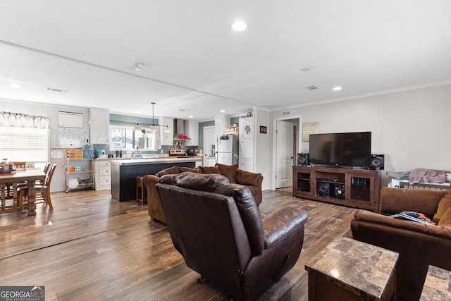 living room with ornamental molding, recessed lighting, and wood finished floors