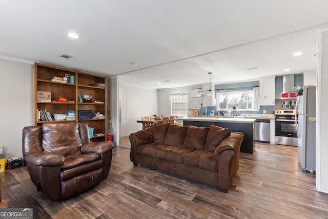 living room featuring ornamental molding, recessed lighting, visible vents, and wood finished floors