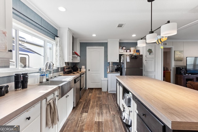 kitchen featuring stainless steel appliances, hanging light fixtures, light countertops, and white cabinetry